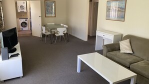 Un espacio habitable compacto con comedor, sofá, televisor y lavadora.