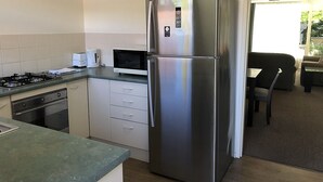 Una cocina compacta con refrigerador de acero inoxidable, microondas y estufa a gas.