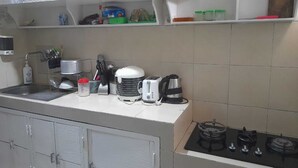 Ett kök med diskho, spis och diverse apparater, inklusive en brödrost och en vattenkokare.