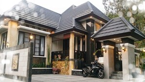 Ett modernt hus med ett mörkt tak, en inglasad veranda och en motorcykel parkerad framför.