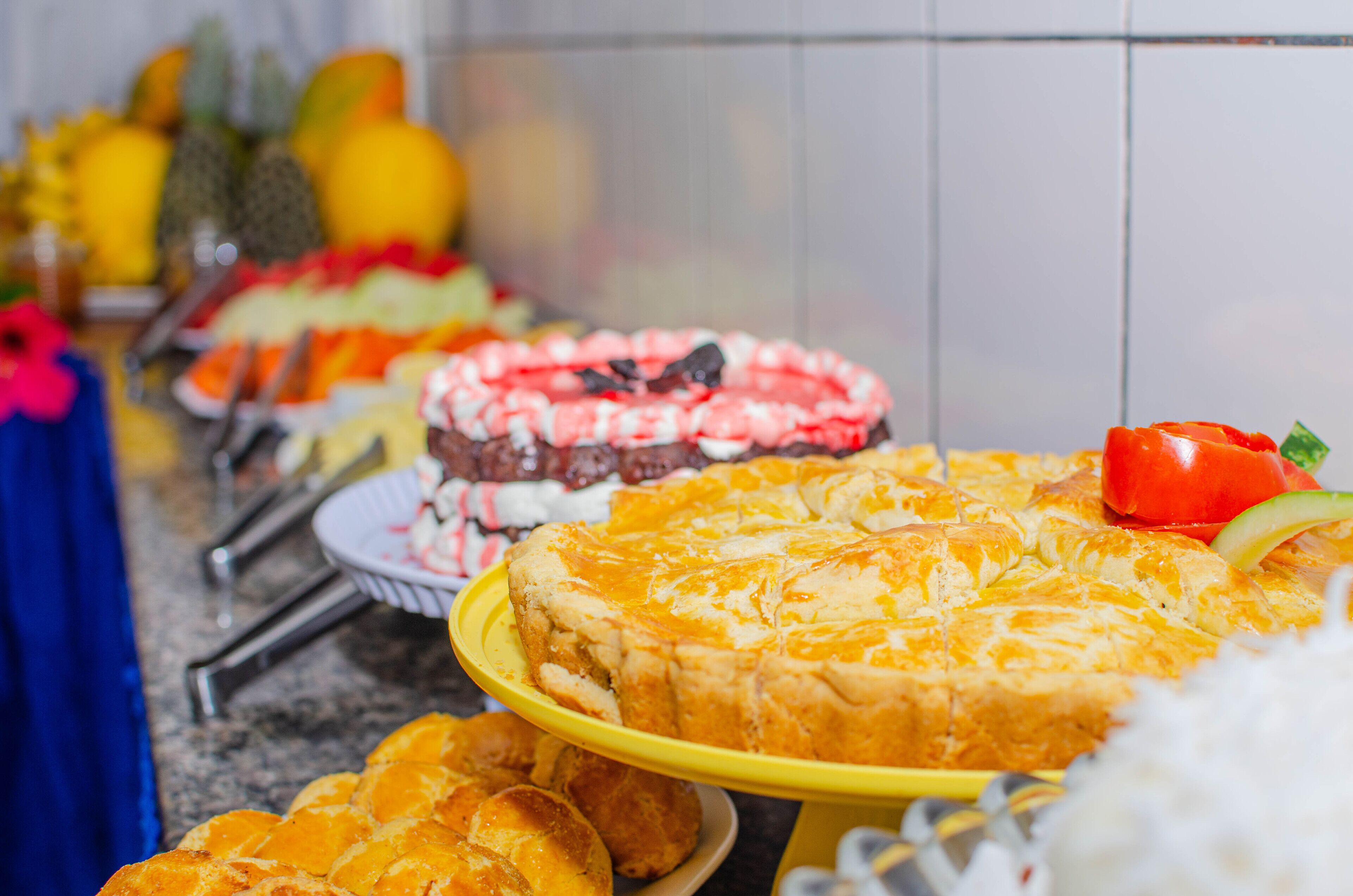 Un tavolo da buffet con diversi piatti, tra cui una grande torta e frutta.