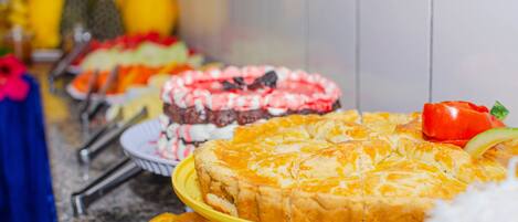 Un tavolo da buffet con diversi piatti, tra cui una grande torta e frutta.