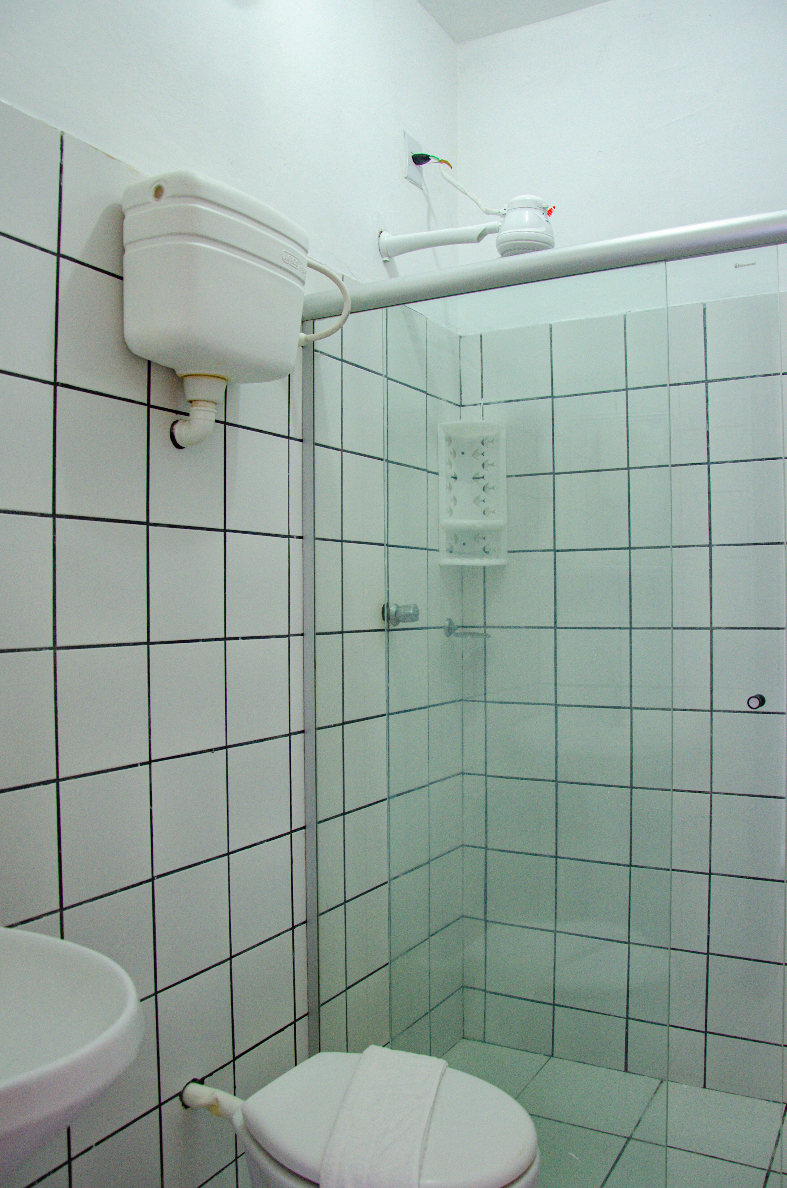 Un baño pequeño con paredes de azulejos, inodoro, lavabo y ducha.