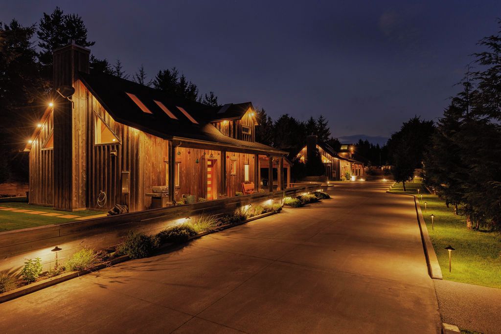 A row of wooden cabins with a covered walkway, surrounded by trees.