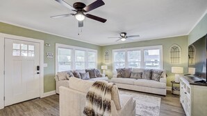 Un salon spacieux avec deux canapés, un ventilateur de plafond et une grande fenêtre.