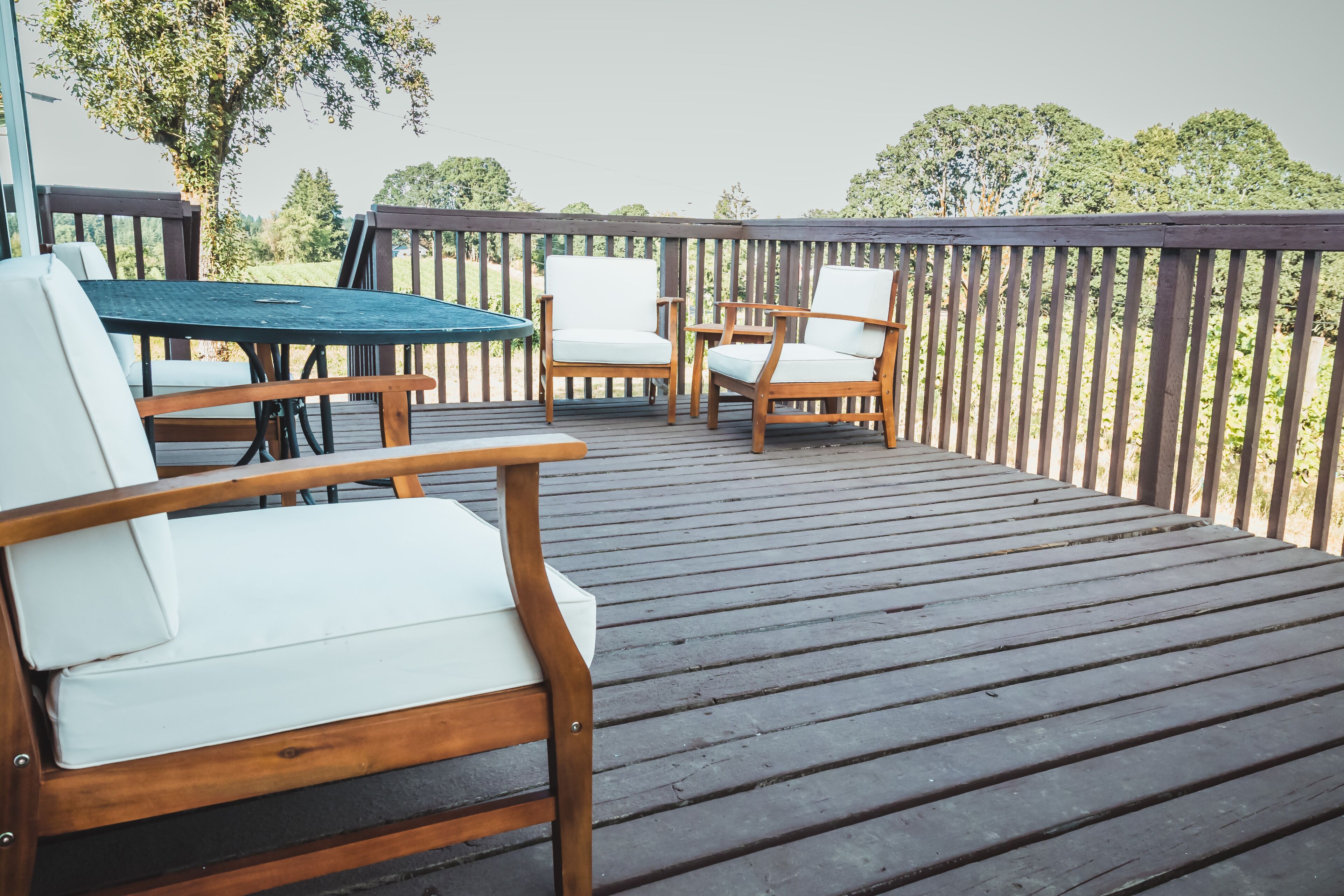 Una terraza de madera con mobiliario exterior, incluyendo una mesa y sillas.