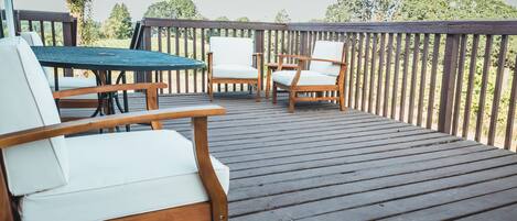 Una terraza de madera con mobiliario exterior, incluyendo una mesa y sillas.