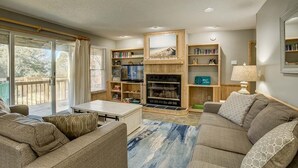 Un salon chaleureux avec un ensemble de canapés, une table basse, une cheminée et une bibliothèque.