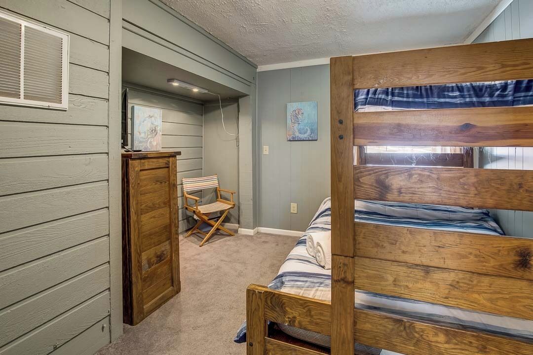 A bedroom with a bunk bed, a desk, and a chair.