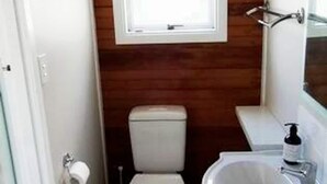 Un baño pequeño con techo de madera, inodoro, lavamanos y ventana.