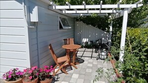 Un patio con una pérgola, una mesa y dos sillas.