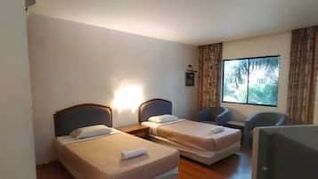 Una habitación de hotel con dos camas individuales, un escritorio, una silla y un ventanal con cortinas.