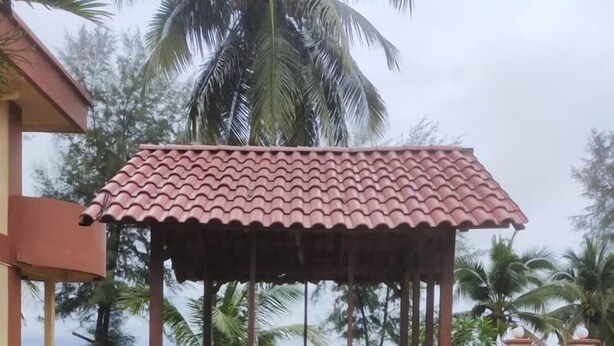 A gazebo with a tiled roof and wooden pillars, surrounded by grass and palm trees. - Seri Indah Resort SDN BHD (Kuala Terengganu)