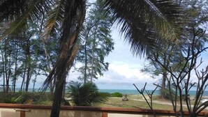 A view from a balcony overlooking a beach with palm trees and a clear sky. - Seri Indah Resort SDN BHD (Kuala Terengganu)