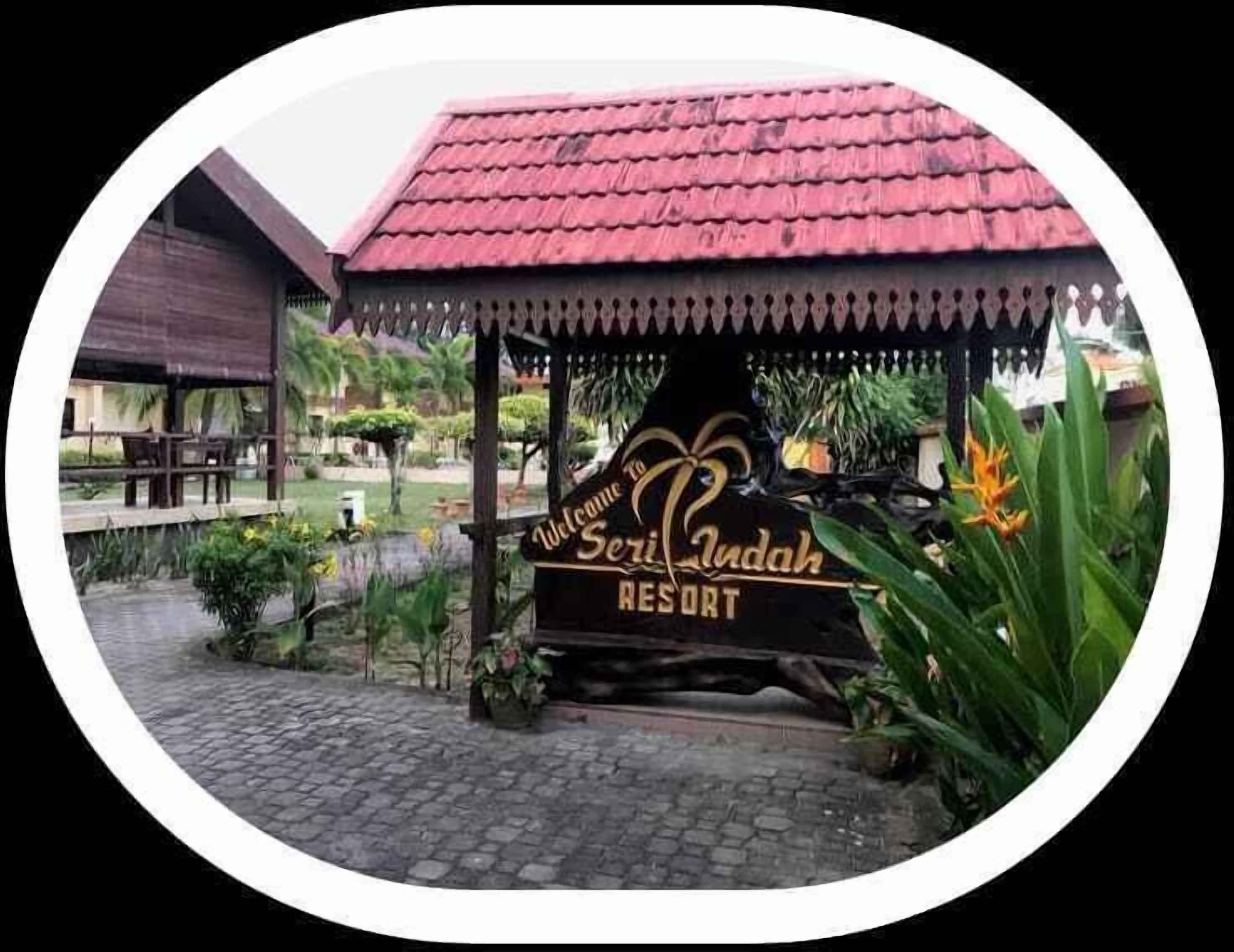 L'ingresso di un resort con tetto rosso e un cartello con la scritta 'Welcome to Seri Kudah Resort'.
