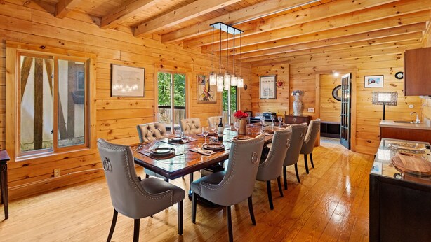 Interior de una cabaña de madera con comedor, paredes de madera y cocina.