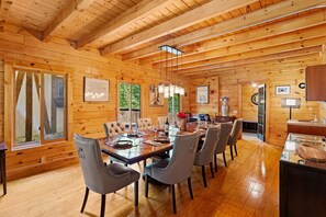 Interior de una cabaña de madera con comedor, paredes de madera y cocina.