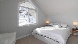 Un dormitorio con una cama individual, dos mesitas de noche y una ventana con persianas.