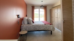 Ein Schlafzimmer mit Bett, Nachttisch, Stuhl, Kleiderschrank und einem Fenster mit Vorhängen.