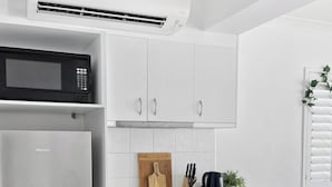 A modern kitchen with white cabinetry, a stainless steel refrigerator, a microwave, and a dishwasher. - Top Spot on Macrossan, Port Douglas 100m to Beach (Port Douglas)