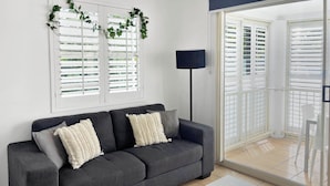 A modern living room with a grey sofa, white cushions, a white coffee table, and a floor lamp. - Top Spot on Macrossan, Port Douglas 100m to Beach (Port Douglas)