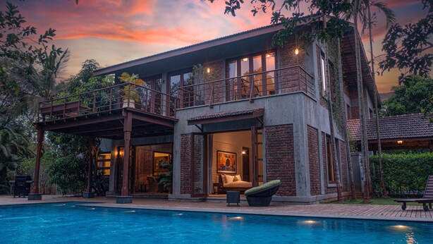 A two-story house with a balcony, a swimming pool, and a garden. - amã Stays & Trails The Mango House, Alibag (Alibag)