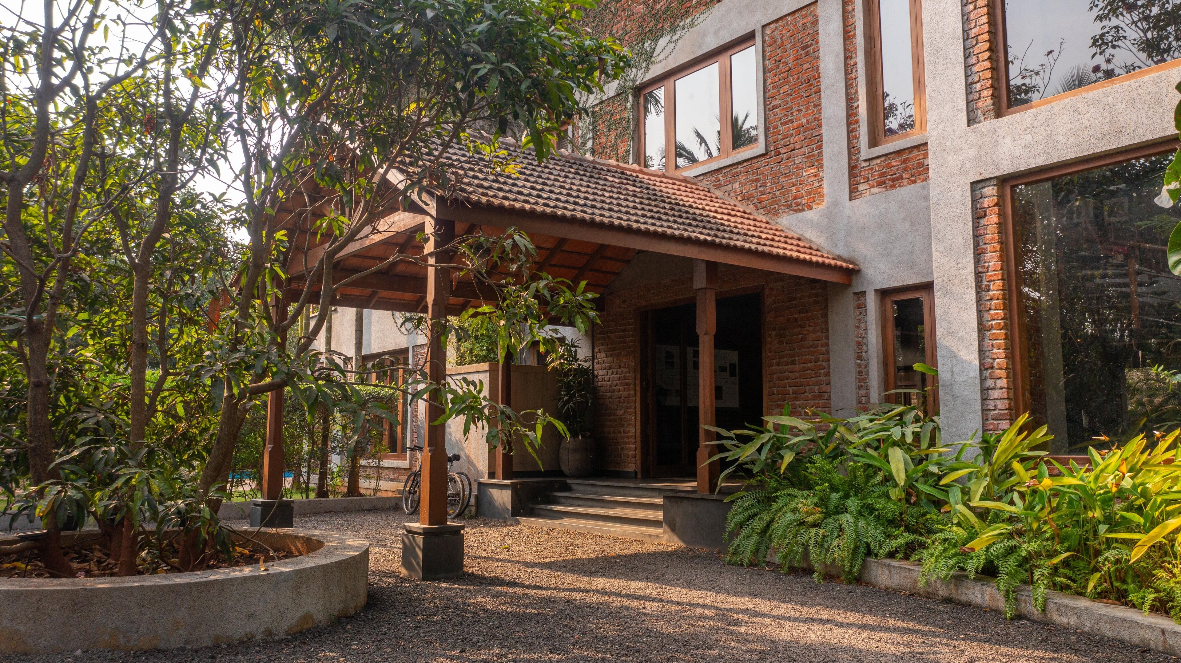 A modern house with a covered patio, a brick exterior, and a gravel driveway.