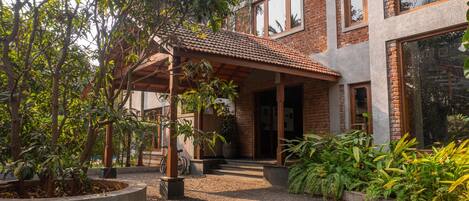 A modern house with a covered patio, a brick exterior, and a gravel driveway.