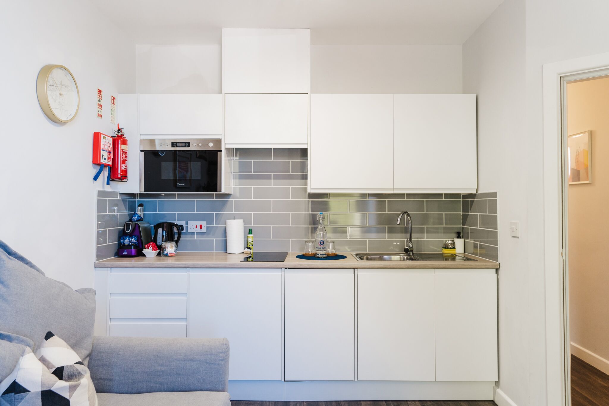 A compact kitchen with white cabinets, a microwave, a sink, and a coffee maker.