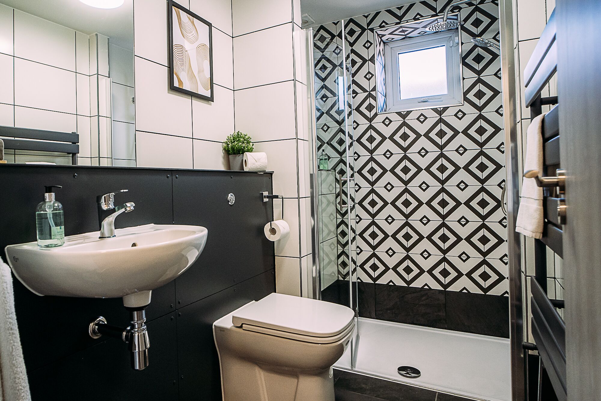 A modern bathroom with a sink, toilet, and shower.