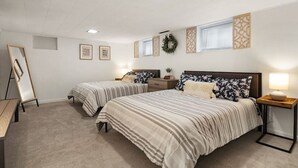 A bedroom with two beds, a desk, and a dresser.