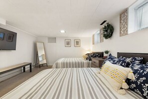 Une chambre avec deux lits, un banc, un miroir et un bureau.