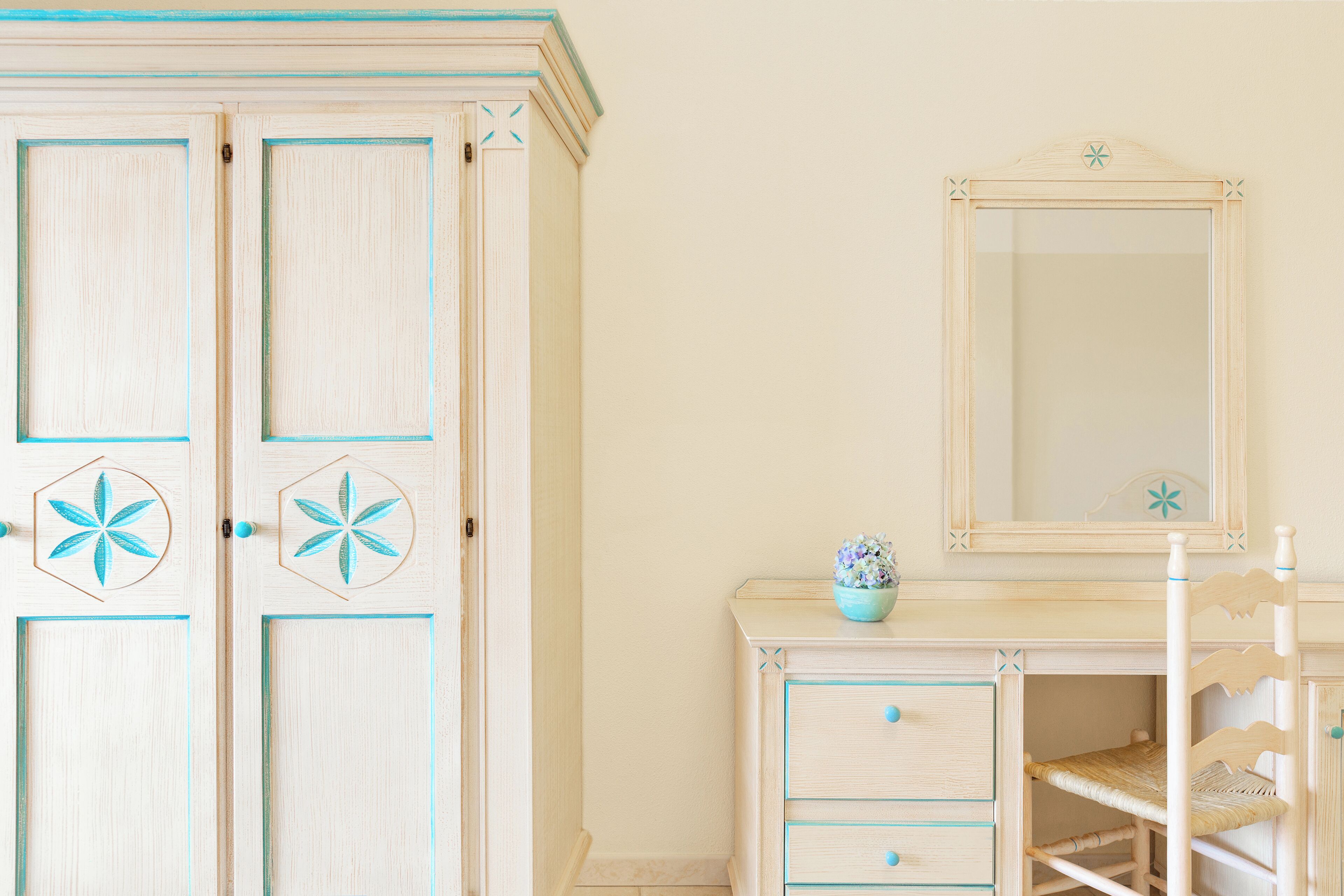 A room with a wooden wardrobe, a dresser, and a mirror.