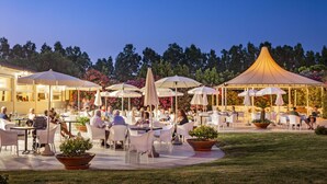 An outdoor dining area with tables and chairs, umbrellas, and potted plants. - Sentido Orosei Beach (Orosei)