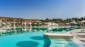 A large, clear swimming pool with a modern design, surrounded by a hotel with multiple balconies and outdoor seating areas. - Sentido Orosei Beach (Orosei)