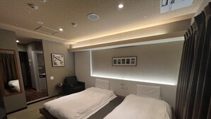 Ett hotellrum med två sängar, ett litet skrivbord, en stol, en spegel och en tavla som hänger på väggen.