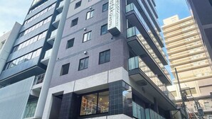 En modern hotellbyggnad med flera våningar, stora fönster och en tydlig skylt som visar att det är Hotaku Hotel.