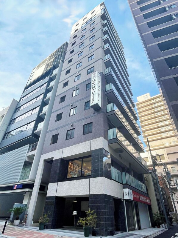 Moderni hotellirakennus, jossa on useita kerroksia, suuret ikkunat ja selkeästi näkyvä Hotaku-hotellin kyltti.