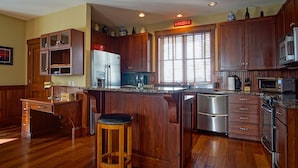 Una cocina con armarios de madera, un refrigerador de acero inoxidable, un microondas y una cafetera.