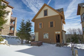 A multi-story building with a stone facade, wooden balconies, and a snow-covered ground.