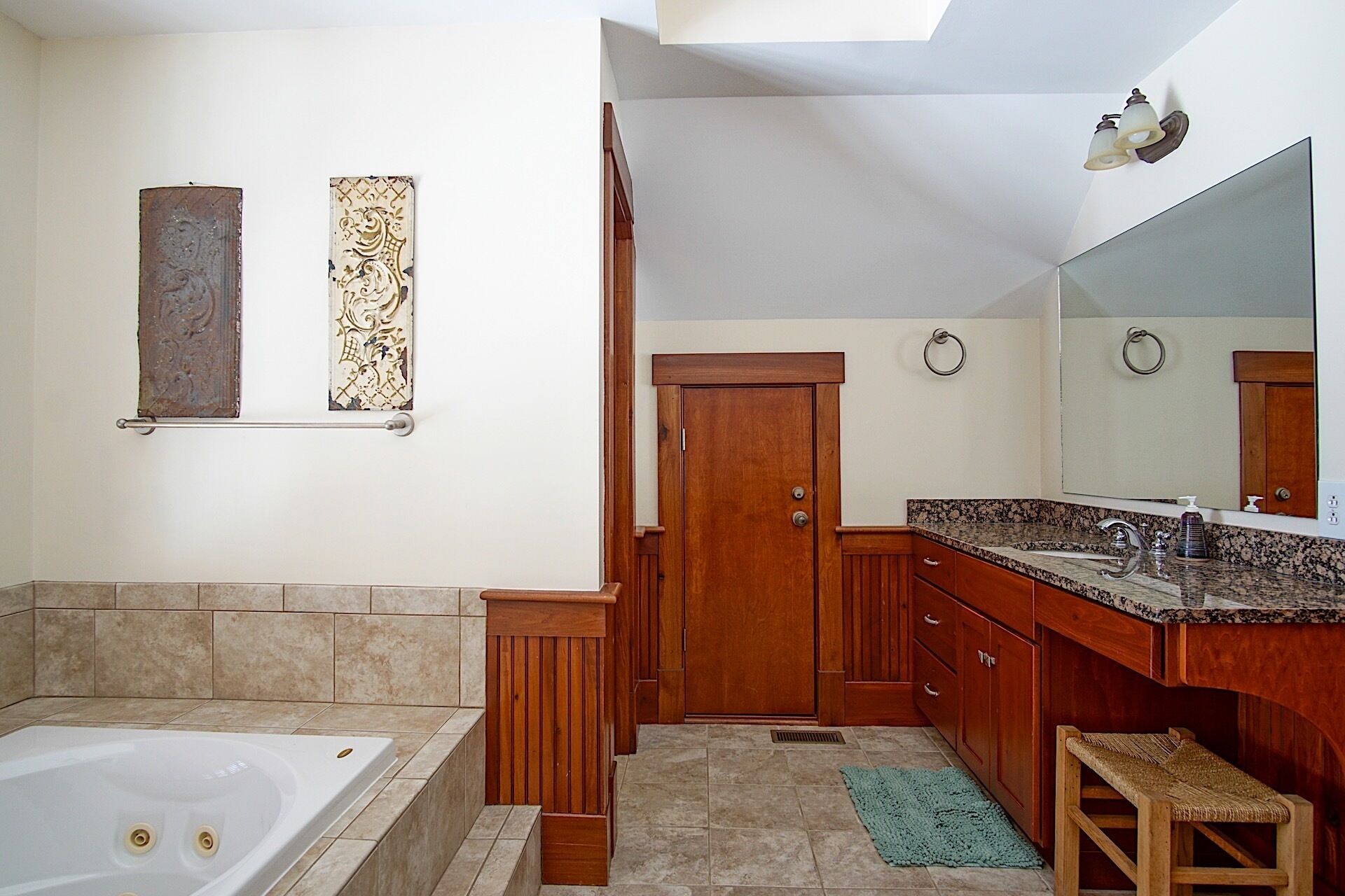 A bathroom with a bathtub, wooden vanity, and a large mirror.