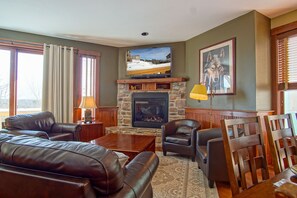 A cozy living room with a fireplace, leather sofas, and a television mounted above it.