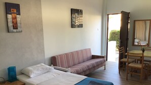 Una camera d'albergo con un letto, un divano, un tavolo da pranzo con sedie e opere d'arte alle pareti.