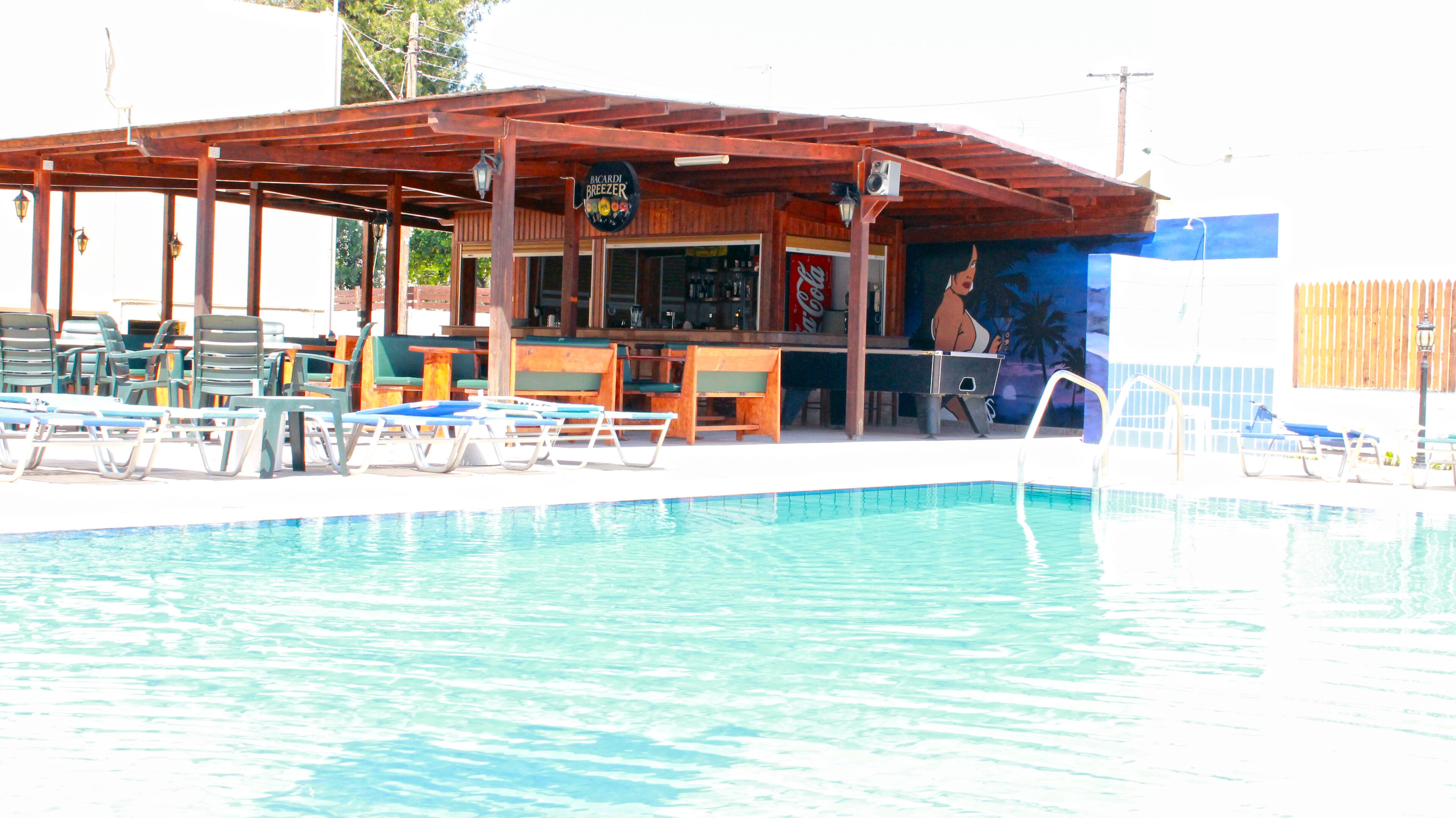 Area piscina con sedie a sdraio e un bar.