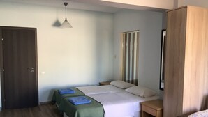 Camera da letto con due letti, un'armadio in legno, un comodino e una lampada a sospensione.