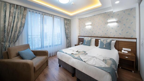 A hotel room with a large bed, a sofa, a nightstand, and a window with curtains. - Lika Hotel - Superior Double or Twin Room - Unforgettable Holiday in Istanbul (Istanbul)
