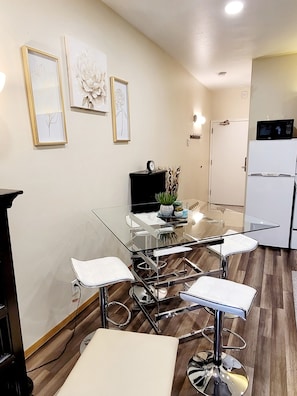 A modern kitchen with a white refrigerator, a microwave, and a dining area with a glass table and white chairs. - 1-bedroom condo,Sundance Festival 5-min to ParkCity Mountain Resort,Deer Valley  (Park City)