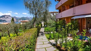 A multi-story building with a garden pathway leading to a pool area. - PELER Beth's House (Brenzone sul Garda)