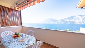 A balcony with a table set for two, overlooking a coastal view. - PELER Beth's House (Brenzone sul Garda)