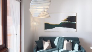 A modern living room with a green sofa, a unique hanging light fixture, and a landscape painting on the wall. - PELER Beth's House (Brenzone sul Garda)